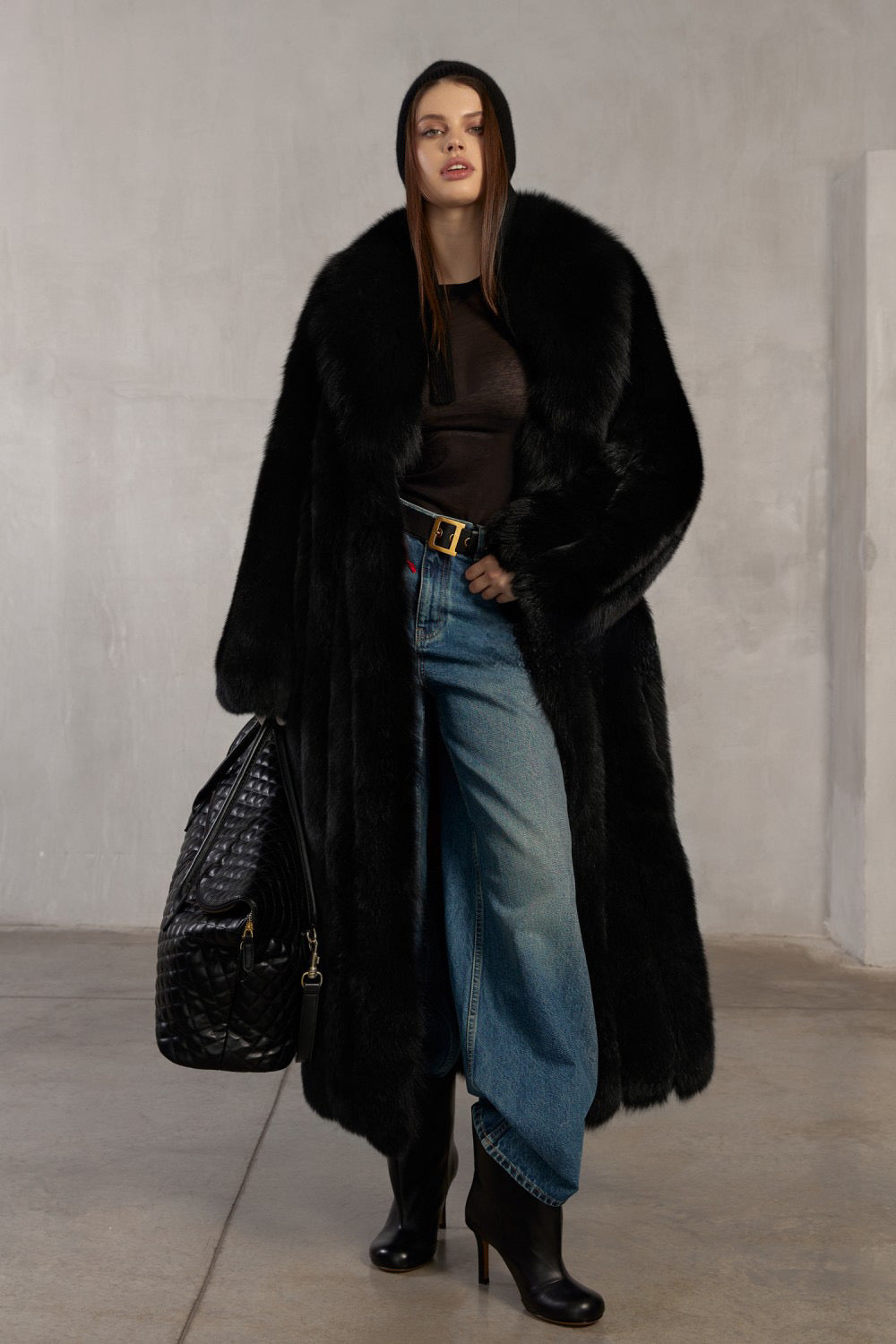 Woman wearing a luxurious long black fox fur coat, styled for bold winter elegance.