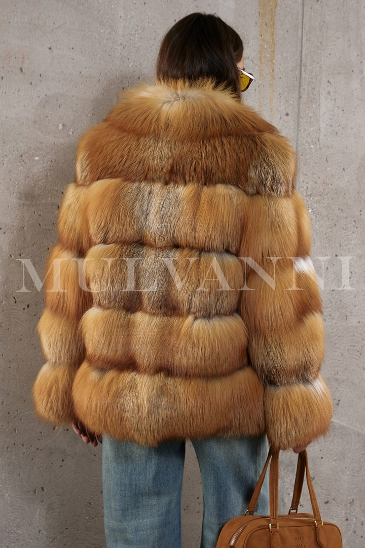 Red fox fur coat styled with denim for a modern take on timeless luxury, worn by a woman with graceful poise.
